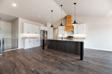 Kitchen in custom home built by Black Hills Homes with wood flooring, granite countertops and lighting.